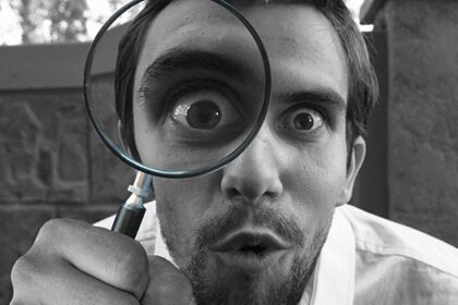 Una persona con una lupa observando algo detalladamente.