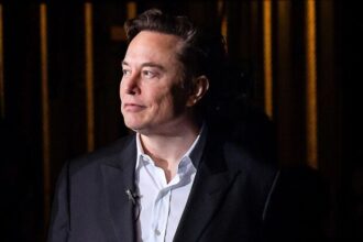 Elon Musk in formal attire against dark background